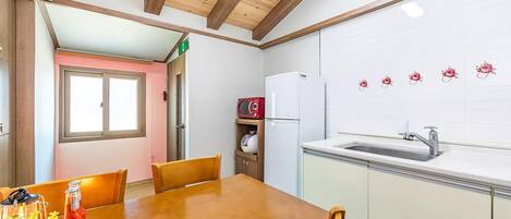 A kitchen with a wooden table, chairs, a refrigerator, a microwave, and a sink.