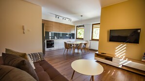 A modern living room with a sofa, a dining table, and a TV.