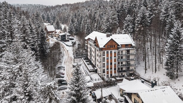 A multi-story building surrounded by snow-covered trees, likely a hotel or resort.