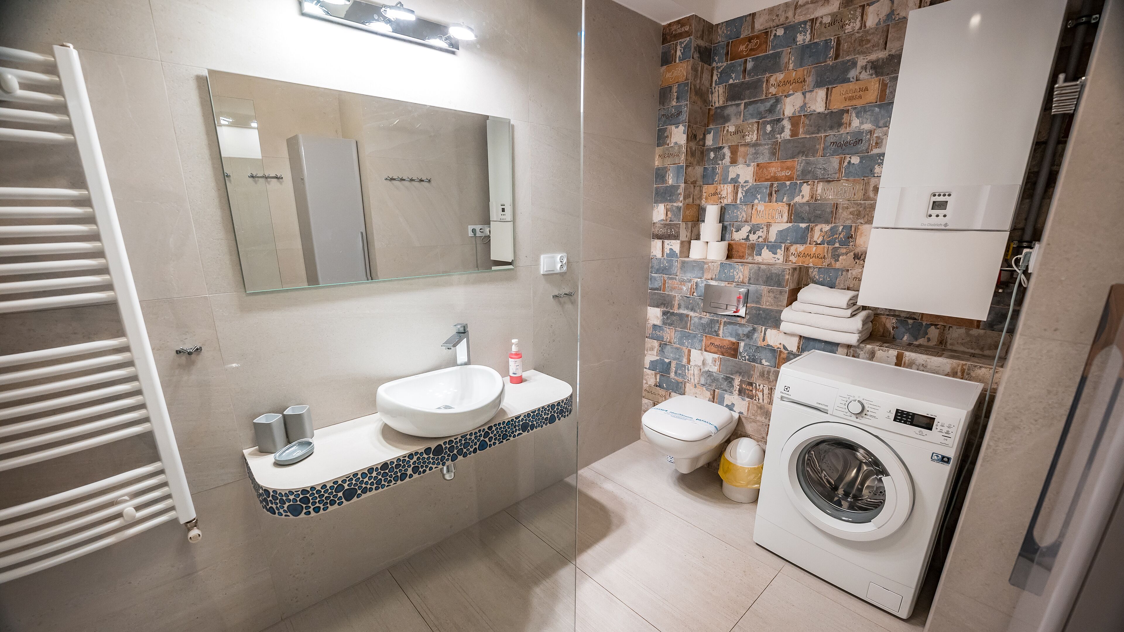 Une salle de bain moderne avec un lavabo blanc, un miroir et un lave-linge encastré.