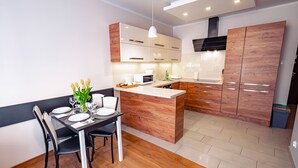 A modern kitchen with wooden cabinets, a central island, and a dining area with a table set for two.