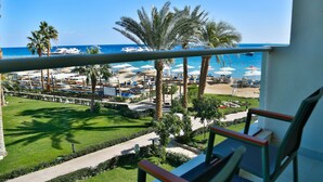 A balcony with a view of a beach, palm trees, and a marina with boats.