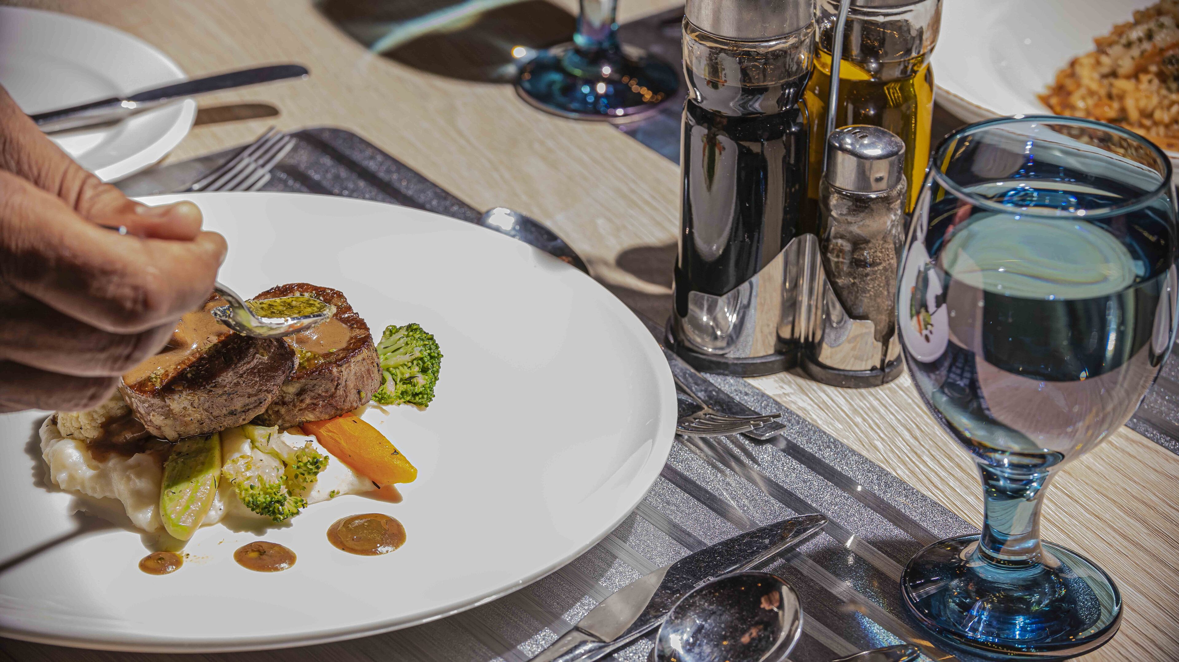 A dining table with a plate of food, cutlery, and a glass of water.