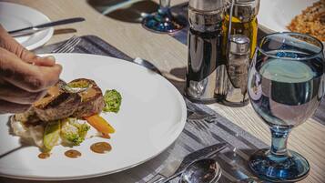 A dining table with a plate of food, cutlery, and a glass of water.