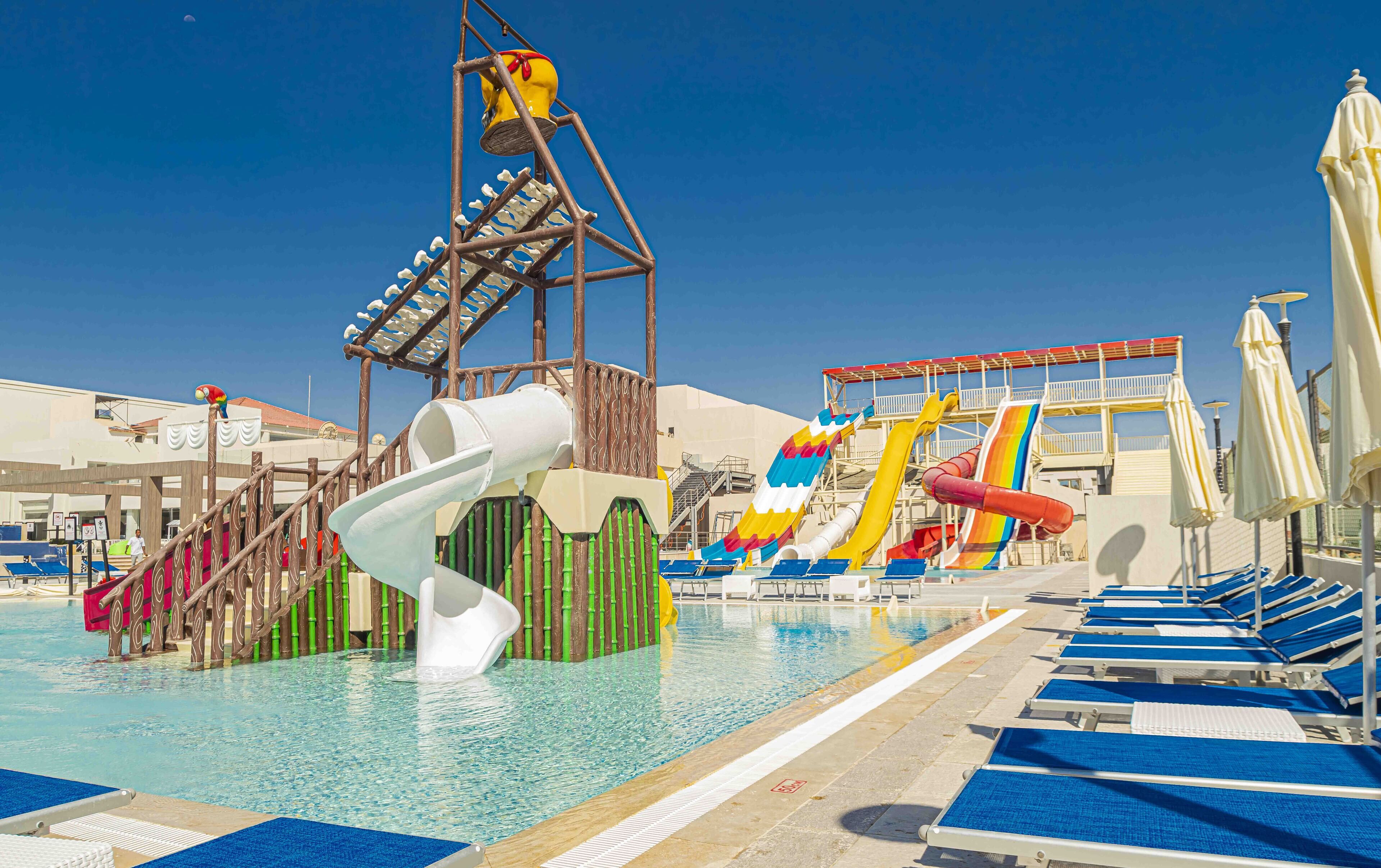 A pool area with water slides, lounge chairs, and a lifeguard tower.