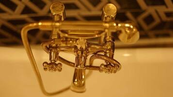 A metallic faucet with three separate spouts and a flexible hose, likely part of a bathroom fixture.