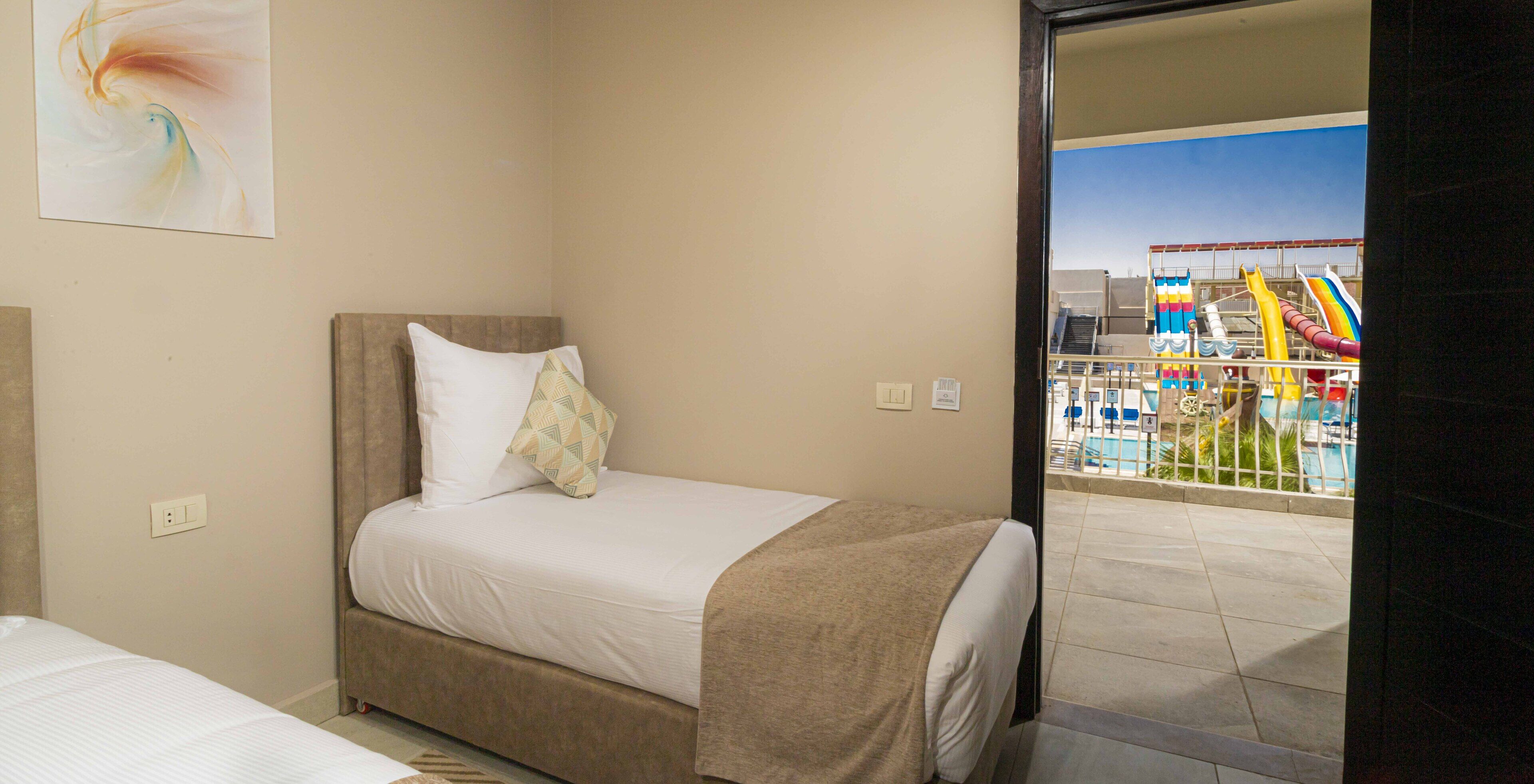Habitación de hotel con cama, vista a una piscina y un tobogán, y un cuadro en la pared.