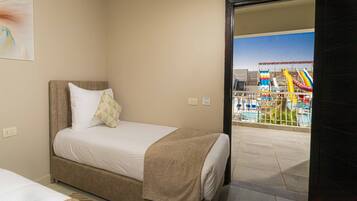 Habitación de hotel con cama, vista a una piscina y un tobogán, y un cuadro en la pared.