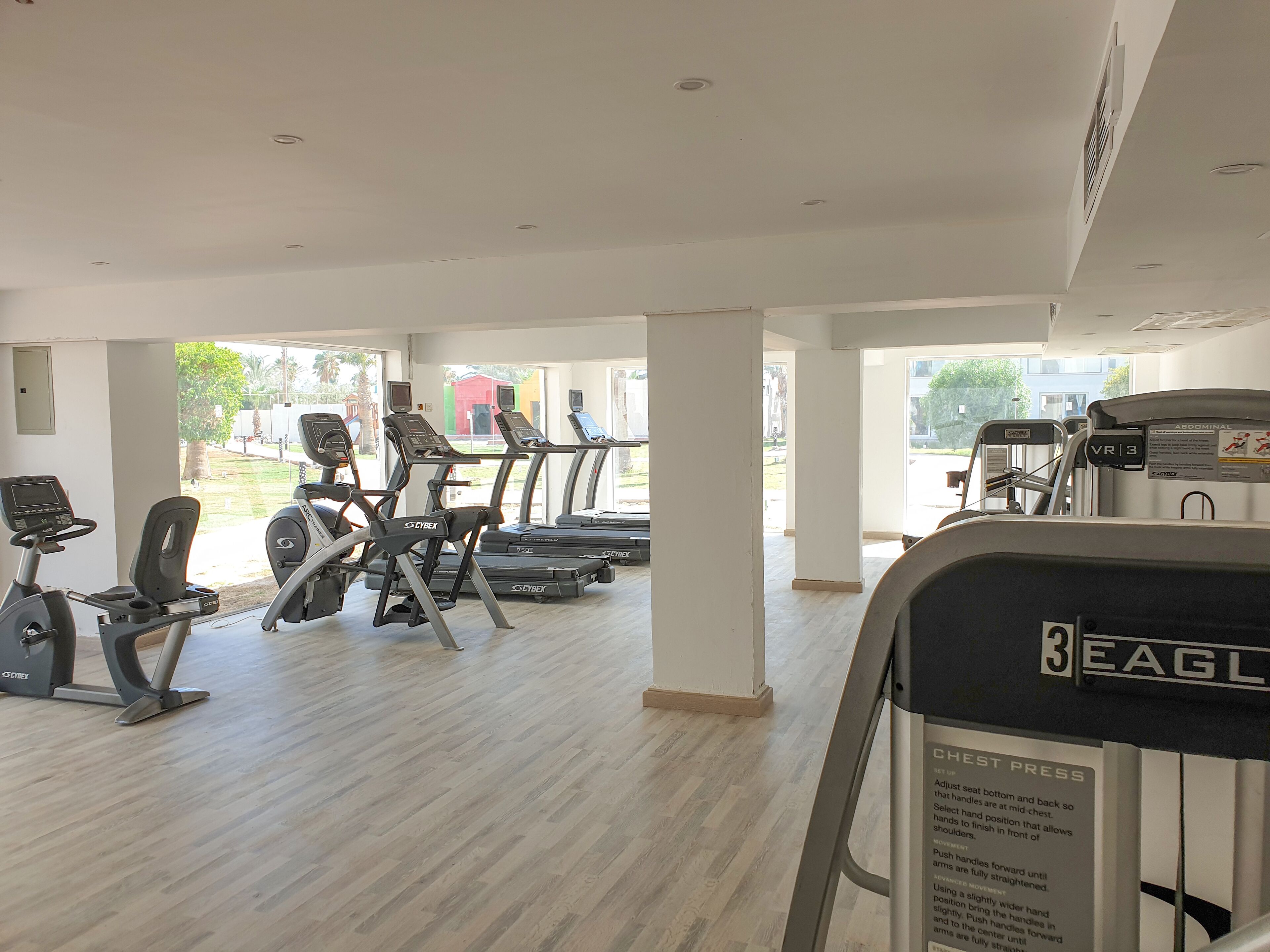 Uma academia com esteiras, bicicletas ergométricas e aparelho de supino.