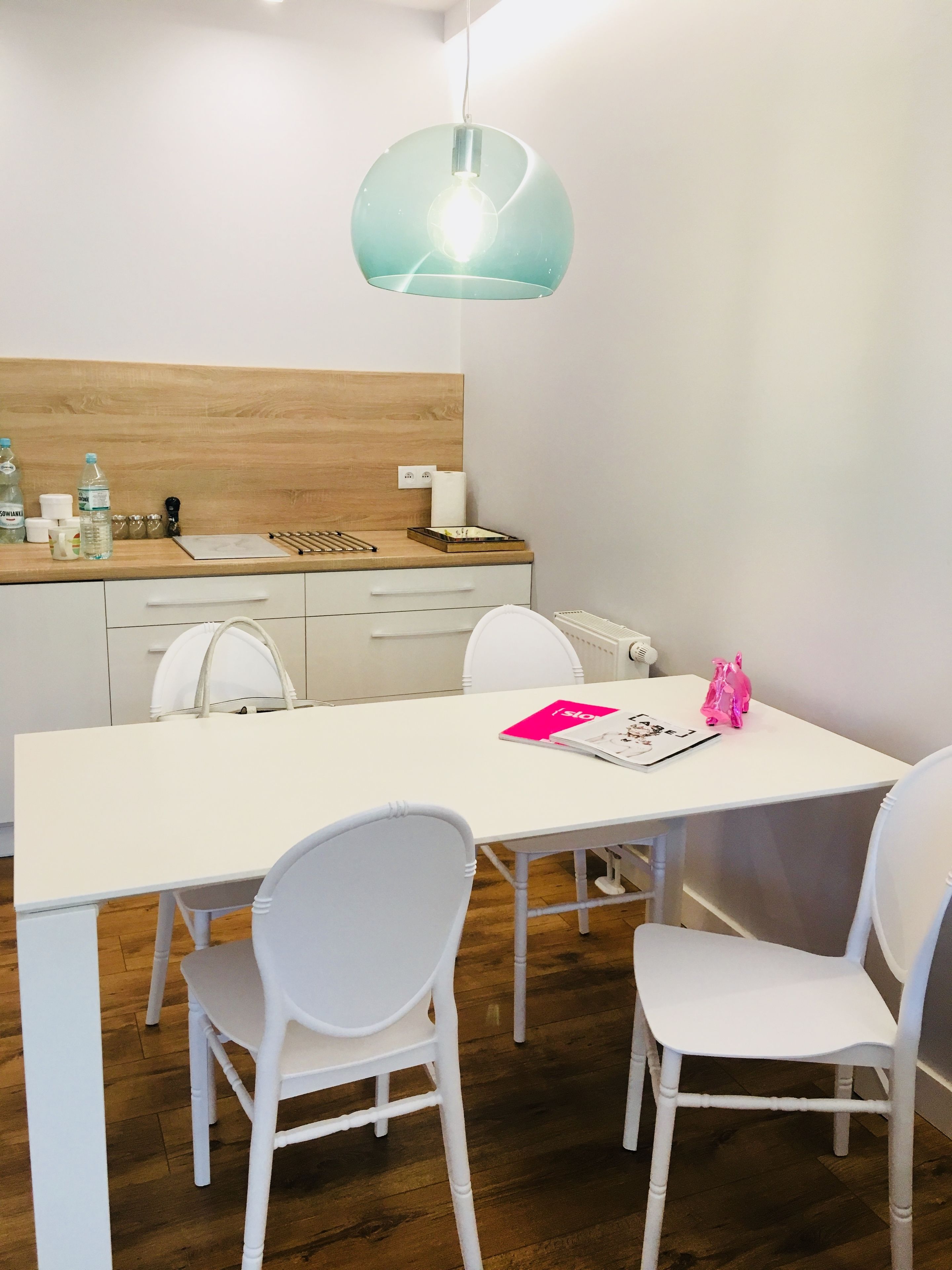 A modern kitchen with white cabinets, a wooden countertop, and a white dining table with chairs.