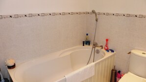 A bathroom with a bathtub, a toilet, and a shower.