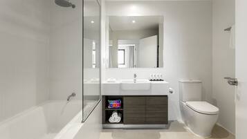 A modern bathroom with a glass-enclosed shower, a vanity with a sink, and a toilet.