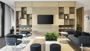 Ein modernes Wohnzimmer mit einem Flachbildfernseher, der an einer Holzwand montiert ist, umgeben von eingebauten Regalen und einem Sofa.