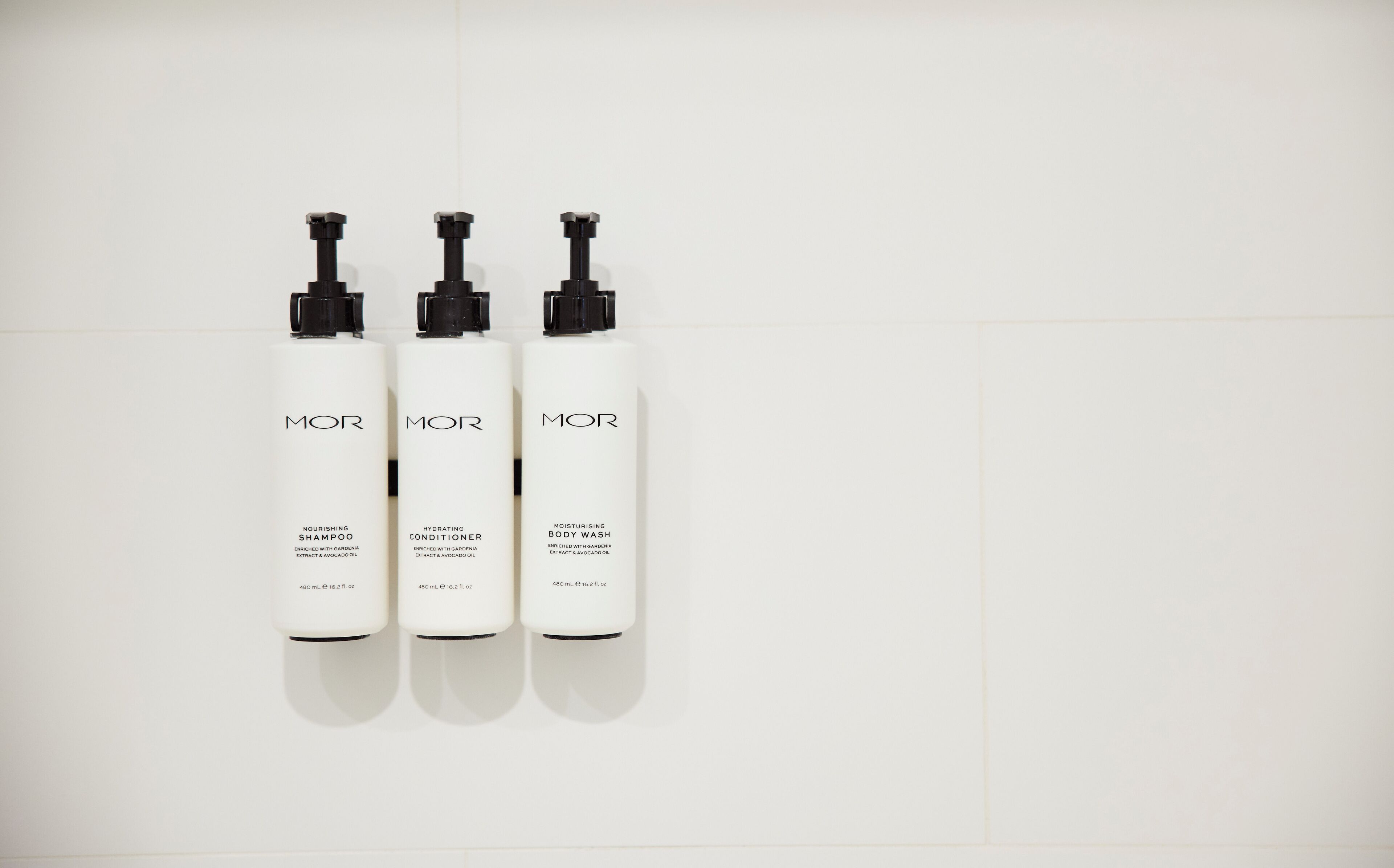 Tres botellas blancas de productos para el cuidado de la piel MOR sobre fondo blanco.