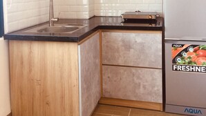 Eine kleine Küche mit Spüle, Holzschränken, einer Arbeitsplatte und einem Kühlschrank.