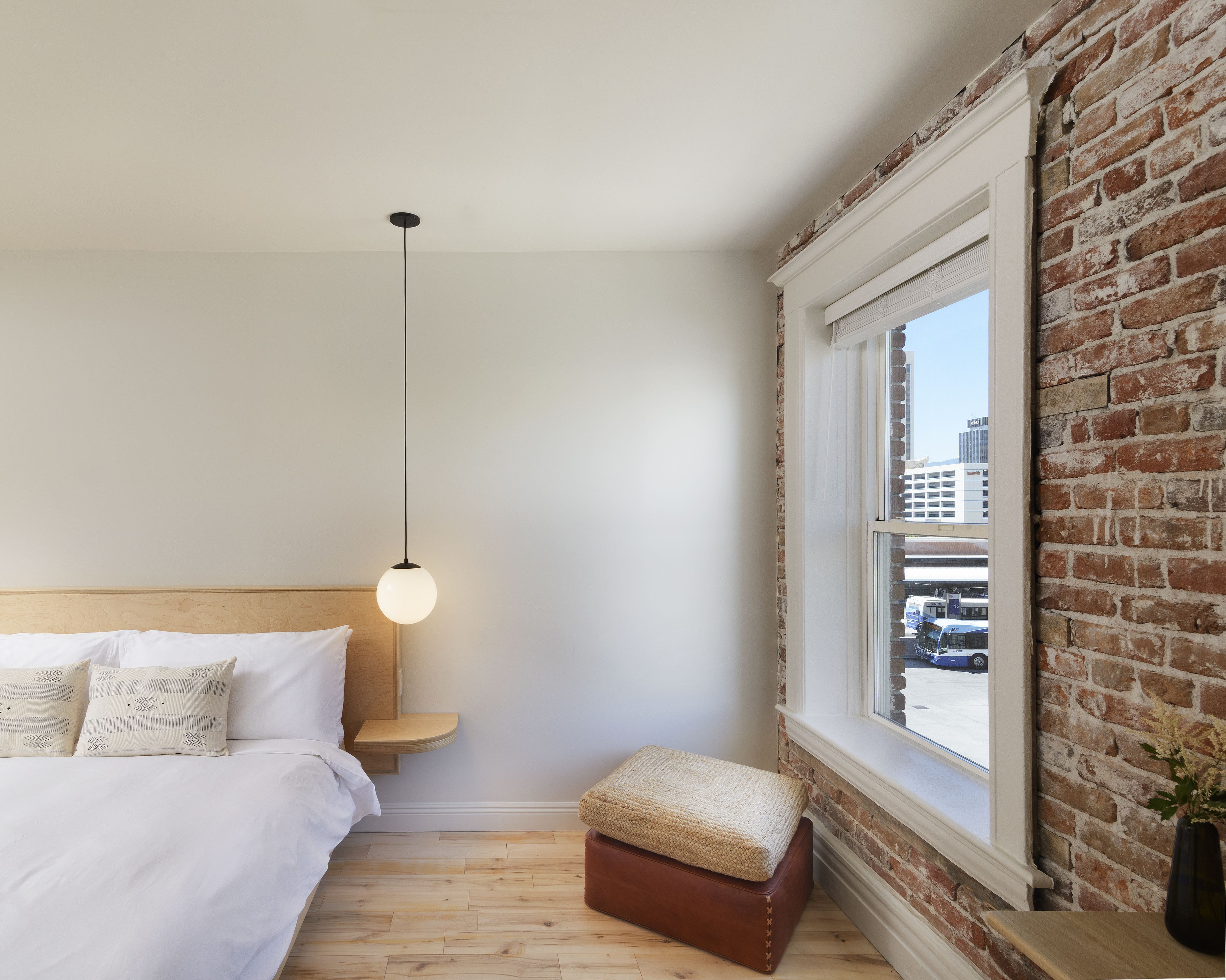A bedroom with a bed, bedside table, and a hanging light fixture.