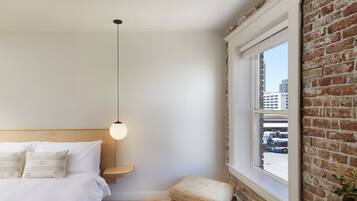 A bedroom with a bed, bedside table, and a hanging light fixture.
