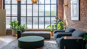 A modern interior with a large window, a round ottoman, a sofa, and hanging pendant lights. - The Jesse Hotel & Bar (Reno)