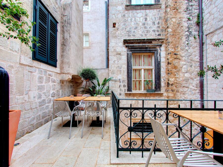 An outdoor café with stone walls, wooden tables, and metal chairs.