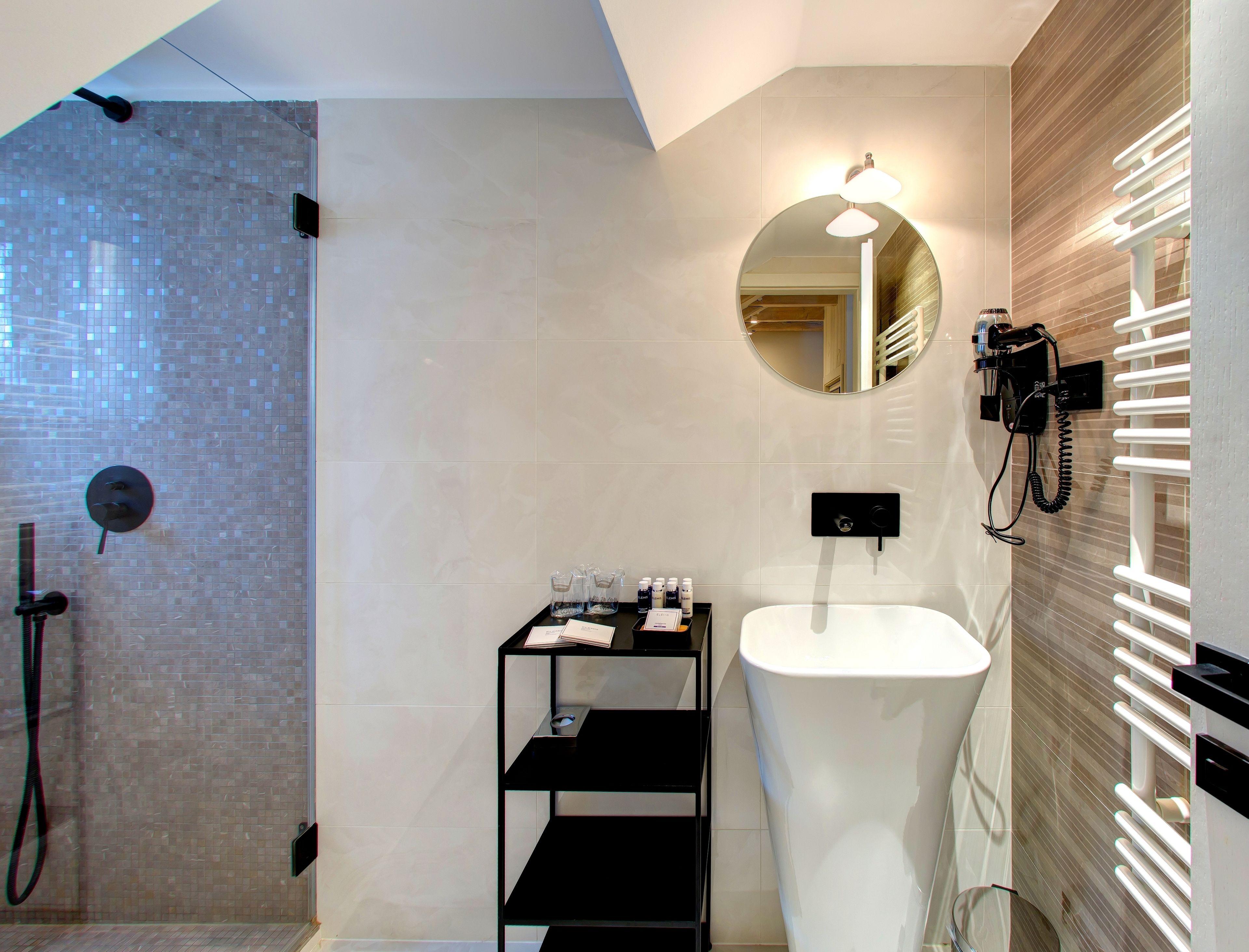A modern bathroom with a glass-enclosed shower, a white sink, and a mirror with integrated lighting.