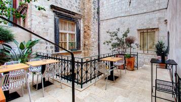 An outdoor café with stone walls, metal furniture, and potted plants.