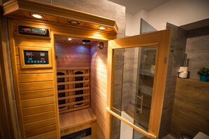 A sauna with a control panel, wooden benches, and a glass-enclosed shower area. - Apartamenty Sun & Snow Zielony Zdrój (Krynica-Zdroj)