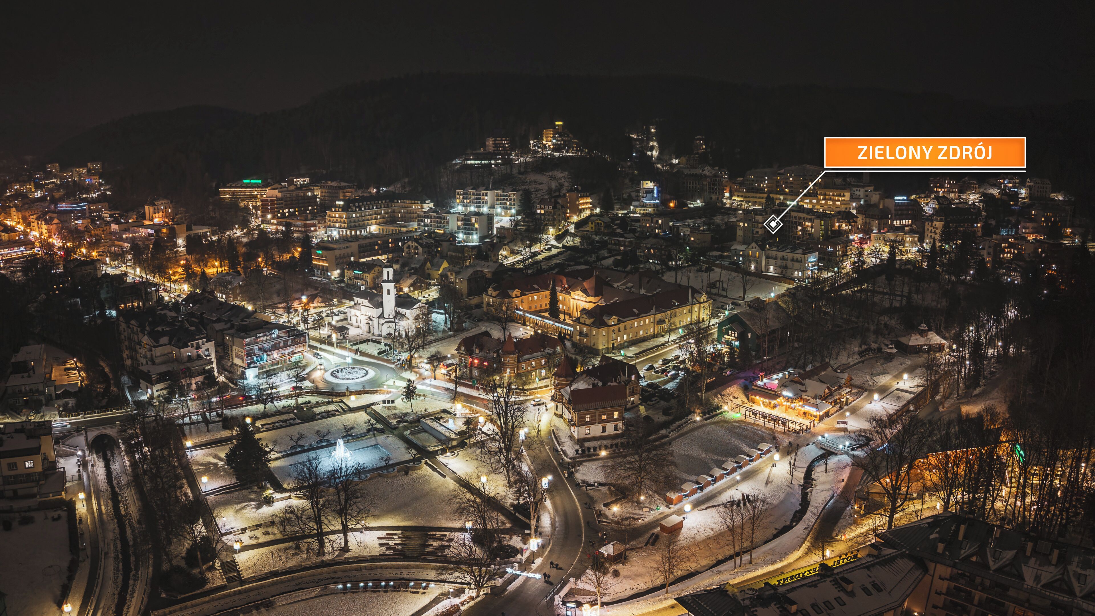 An aerial view of a city at night with illuminated buildings and streets.
