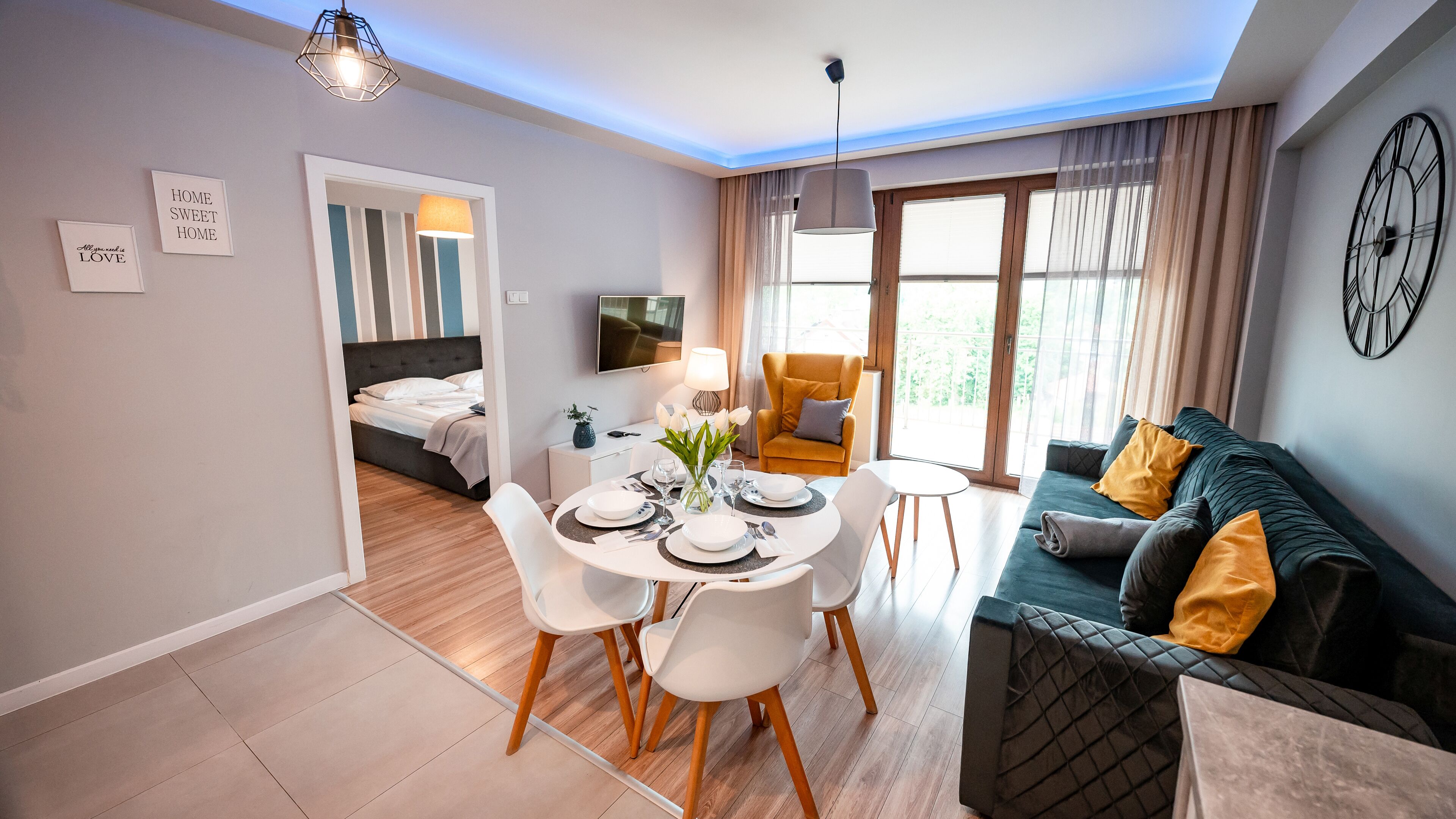 A modern hotel room with a dining area, a sofa, and a bed.