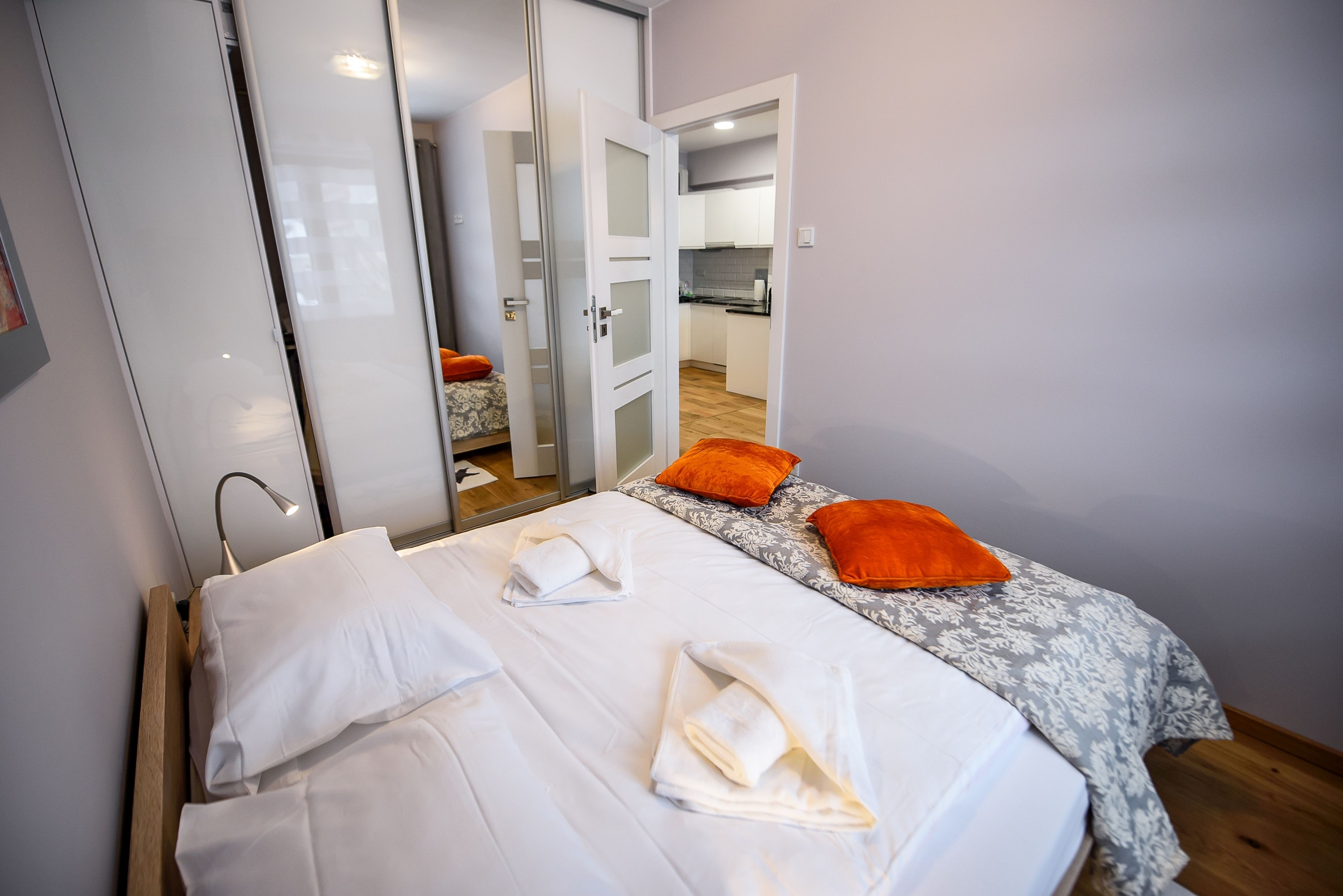 A hotel room with a bed, two pillows, a nightstand, and a mirror.