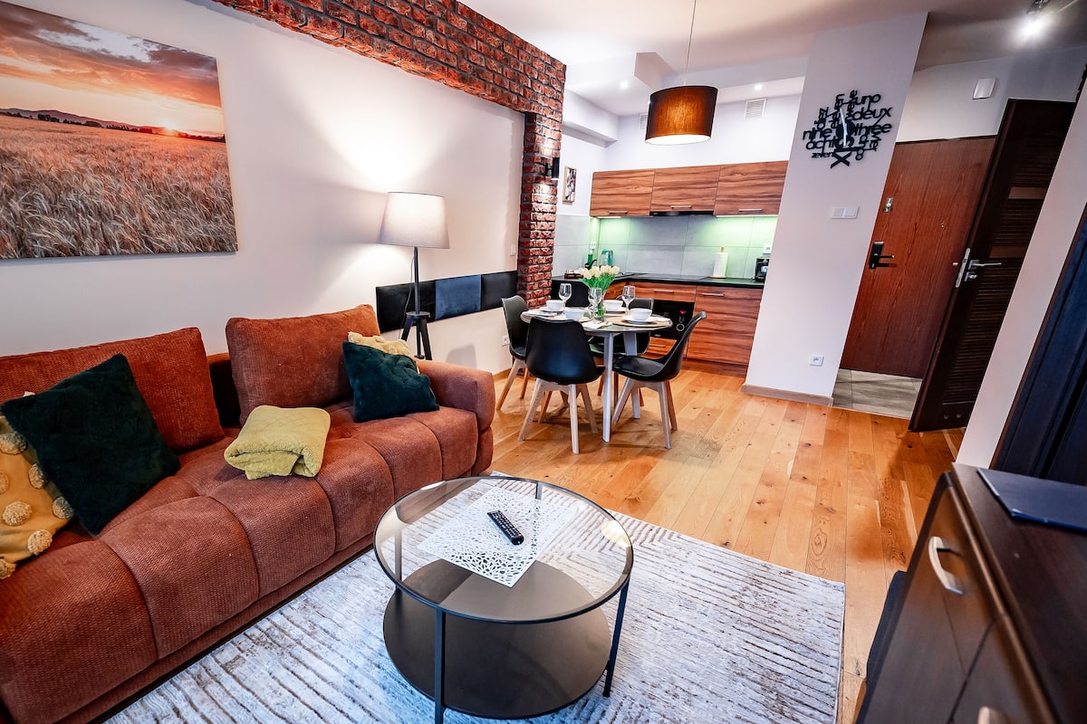 Un salon moderne avec un canapé, une table basse et un tableau représentant un champ.