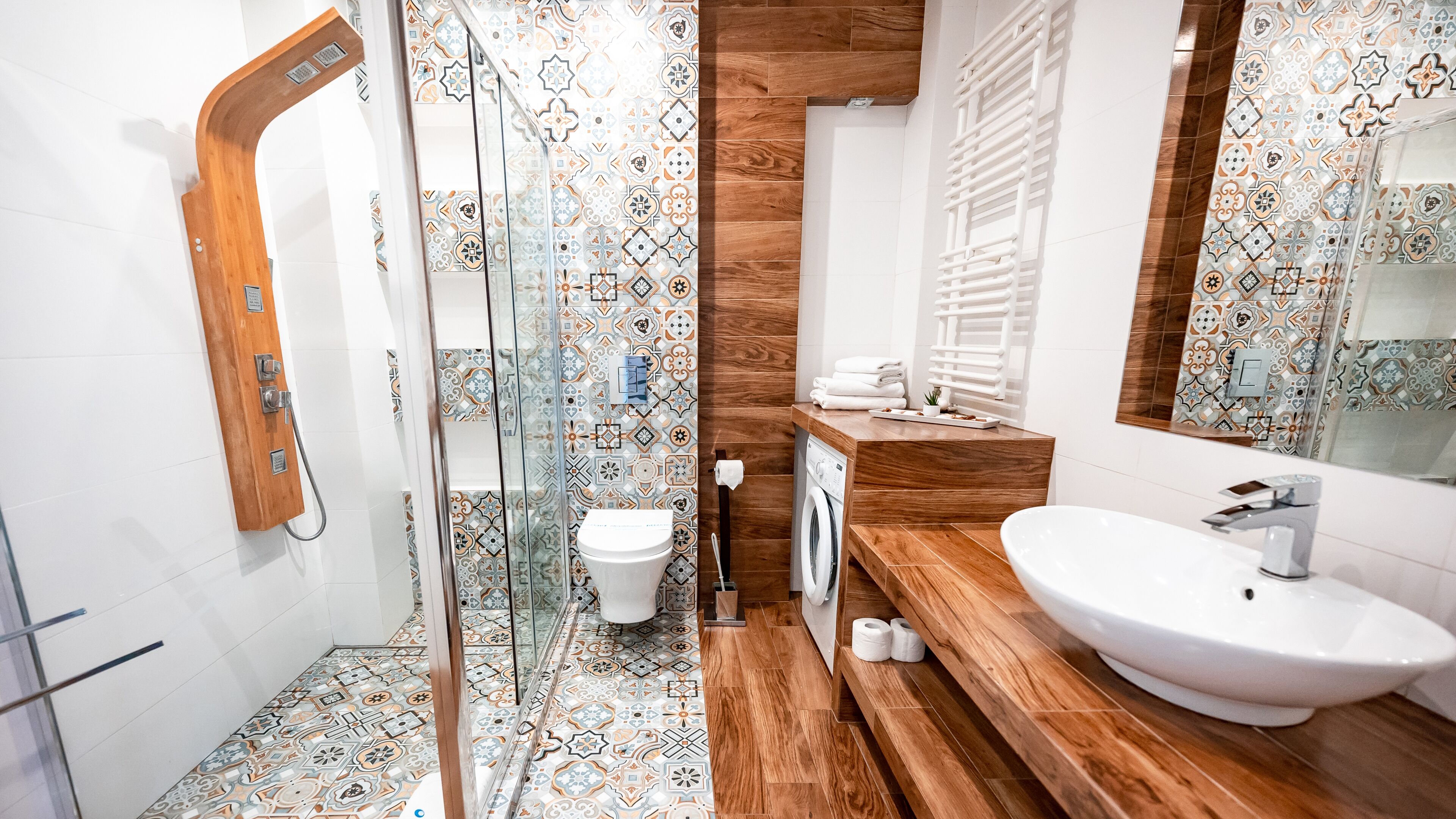 A modern bathroom with a glass shower enclosure, a wooden vanity, a white sink, and a toilet.