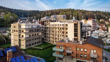 Ein mehrgeschossiges Hotel mit Balkonen, einem Dachgarten und Solaranlagen.