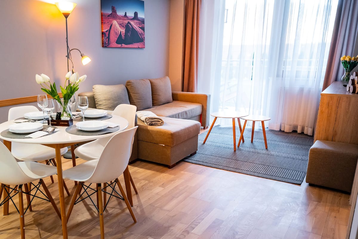 Un coin repas avec une table dressée pour quatre personnes, un canapé et une petite table d’appoint.