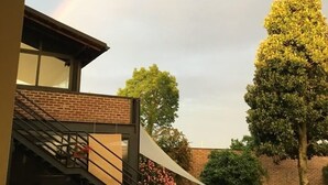 A building with a staircase, a tree, and a rainbow in the background. - Agriturismo La Morosina (Abbiategrasso)