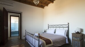 A bedroom with a metal bed frame, a bedside table with a lamp, and a patterned rug. - Agriturismo La Morosina (Abbiategrasso)