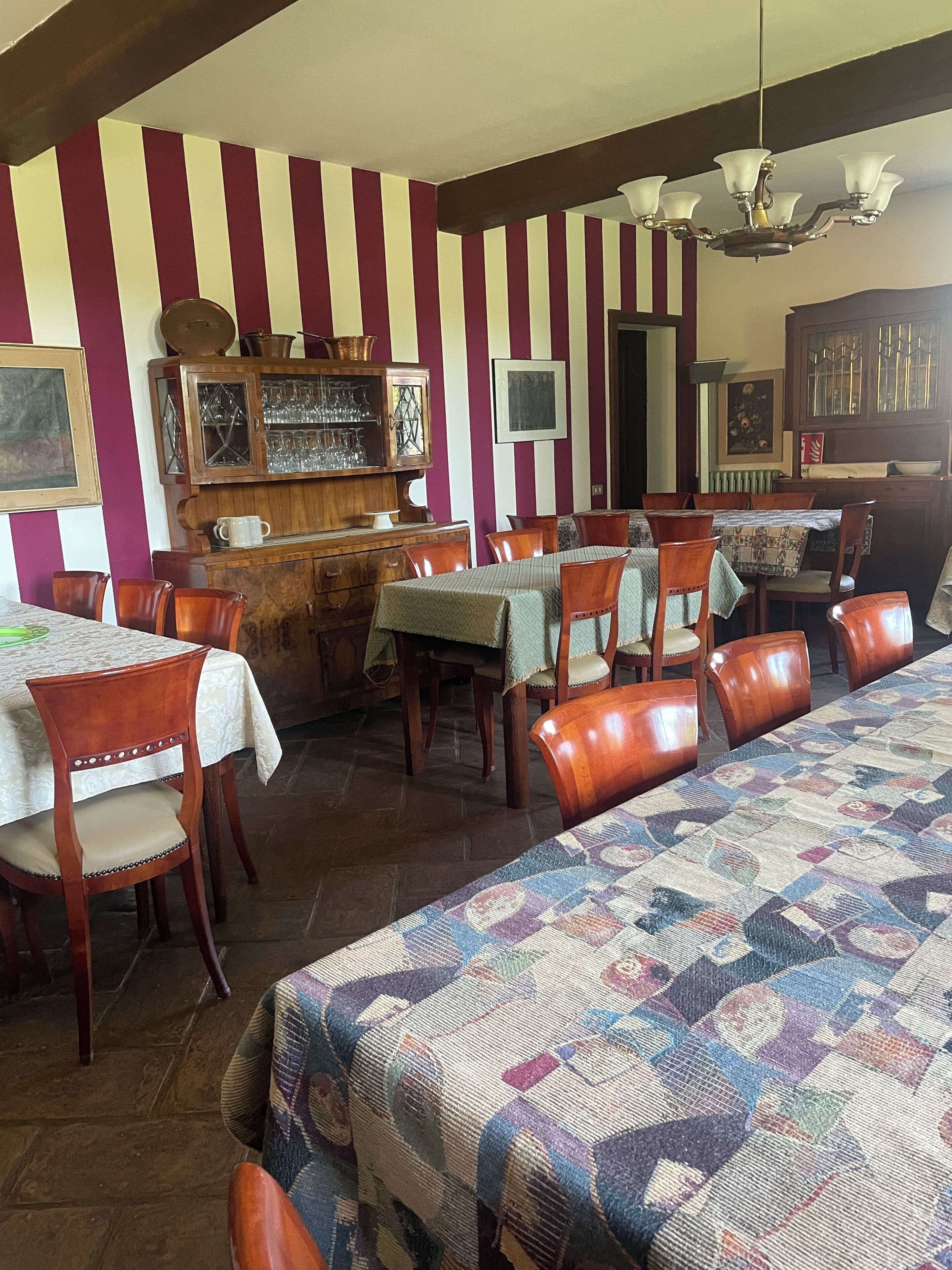 Comedor con paredes a rayas, muebles de madera y una mesa larga.