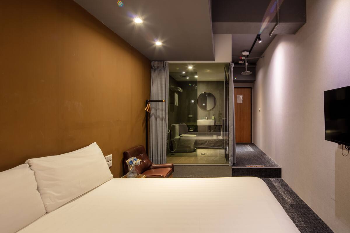 A modern hotel room with a large bed, a desk, and a television.