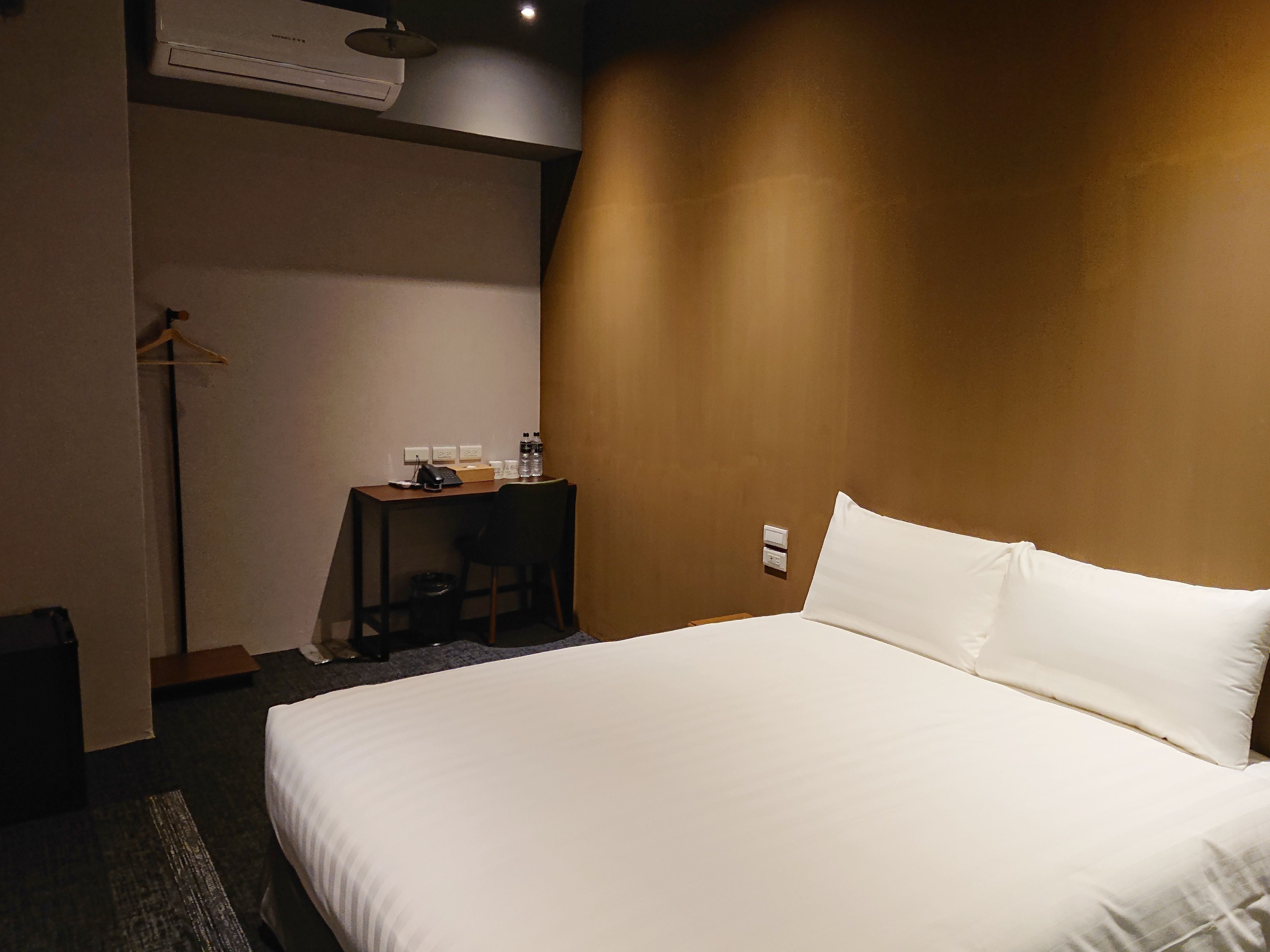 Une chambre d’hôtel avec un grand lit, un bureau avec une chaise et une petite table avec une lampe.