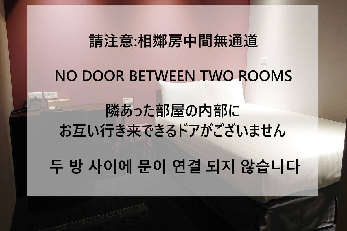 A hotel room with a bed, bedside table, and a phone.