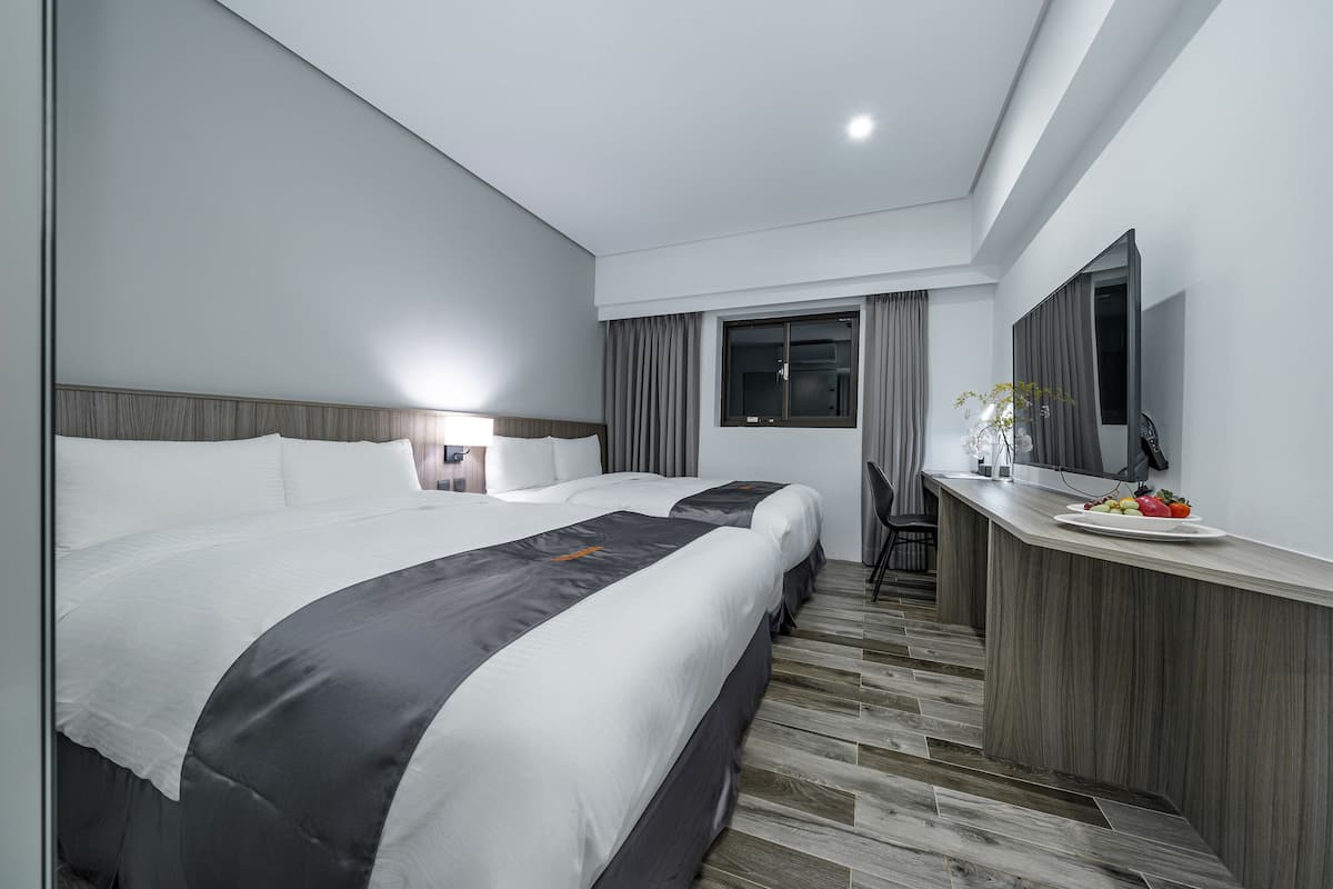Ein modernes Hotelzimmer mit einem großen Bett, einem Schreibtisch mit Spiegel und einer kleinen Essecke.
