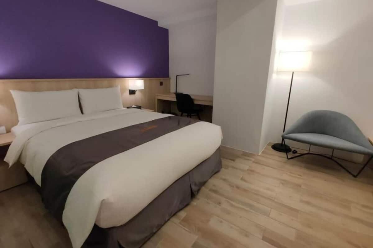 Ein modernes Hotelzimmer mit einem großen Bett, einem Schreibtisch und einem Stuhl.