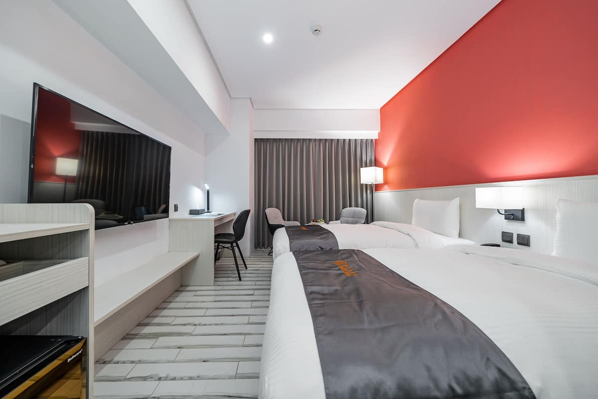 Ein modernes Hotelzimmer mit einem großen Bett, einem Schreibtisch und einem Stuhl.
