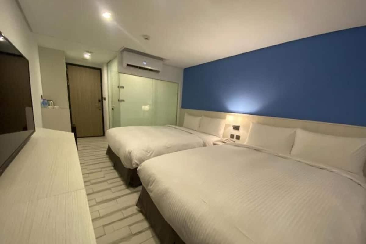 Ein Hotelzimmer mit zwei Betten, einem Schreibtisch und einem Kleiderschrank.