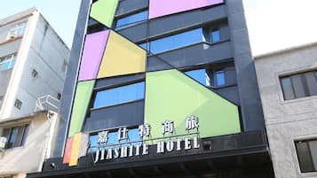 A hotel with a modern facade featuring geometric patterns and a prominent sign in both English and another language.