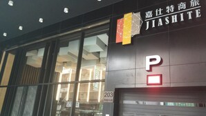 Eine Gebäudefassade mit einem großen, beleuchteten 'P'-Schild, das einen Parkplatz kennzeichnet.
