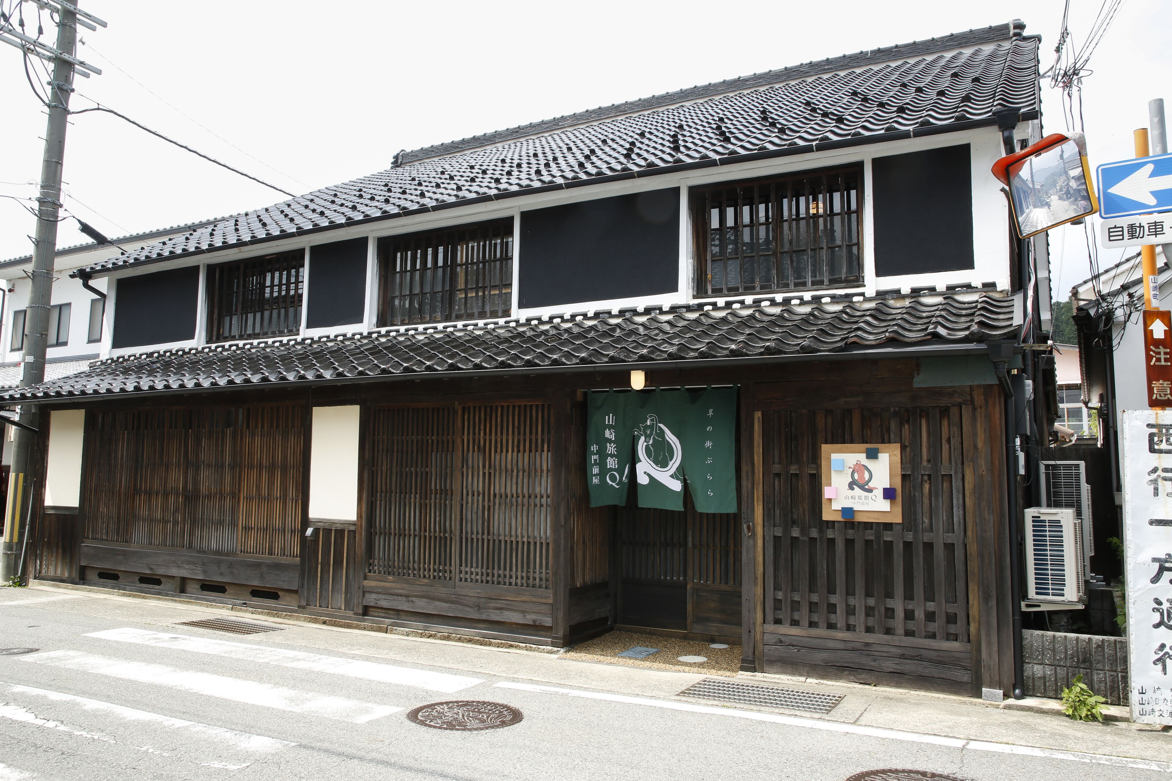 A traditional Japanese building with a tiled roof, wooden sliding doors, and a sign indicating a parking area.