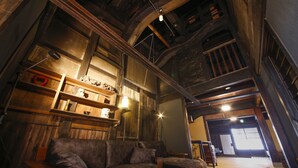 A rustic interior with exposed wooden beams, a sofa, and shelves with various items. - Yamasaki Ryokan Q Nakamonzenya (Shiso)