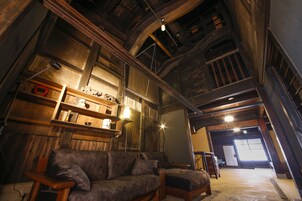 A rustic interior with exposed wooden beams, a sofa, and shelves with various items.