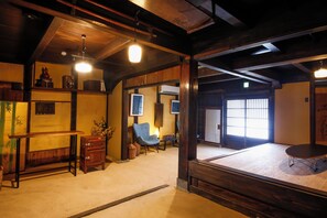 Une pièce de style japonais traditionnel, avec un sol recouvert de tatamis, une basse table en bois, une chaise bleue et un meuble en bois.