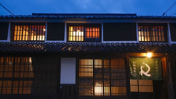 A traditional Japanese building with multiple windows, a tiled roof, and a signboard. - Yamasaki Ryokan Q Nakamonzenya (Shiso)